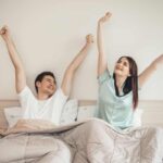 caucasian couple stretching bed smile 1 Mattress Myths Full vs Queen Mattress Mattress Myths That Could Be Ruining Your Sleep
